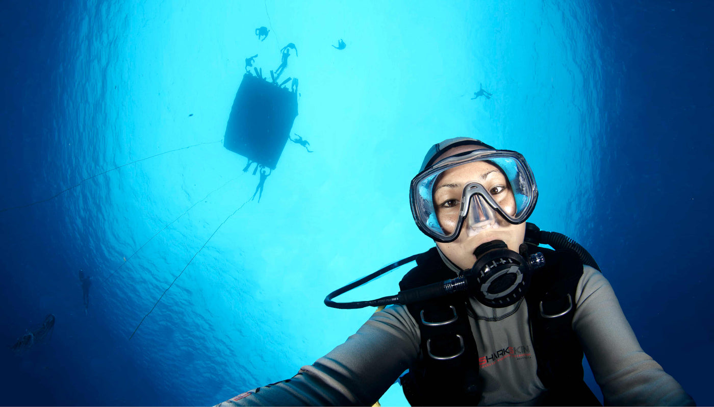 Female diver wearing a Sharkskin Chillproof Top deep below the surface